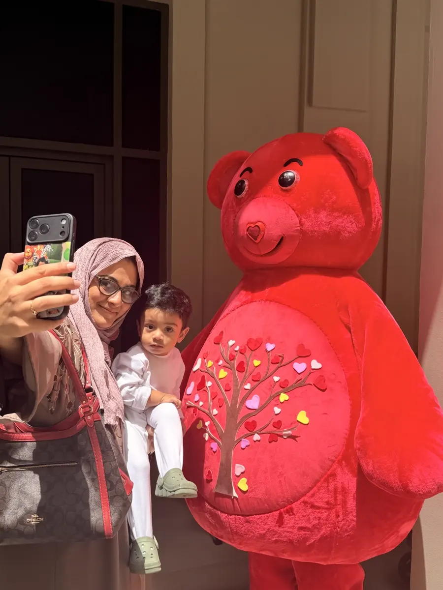 Mother taking a selfie with her toddler and the red YogaBears mascot character