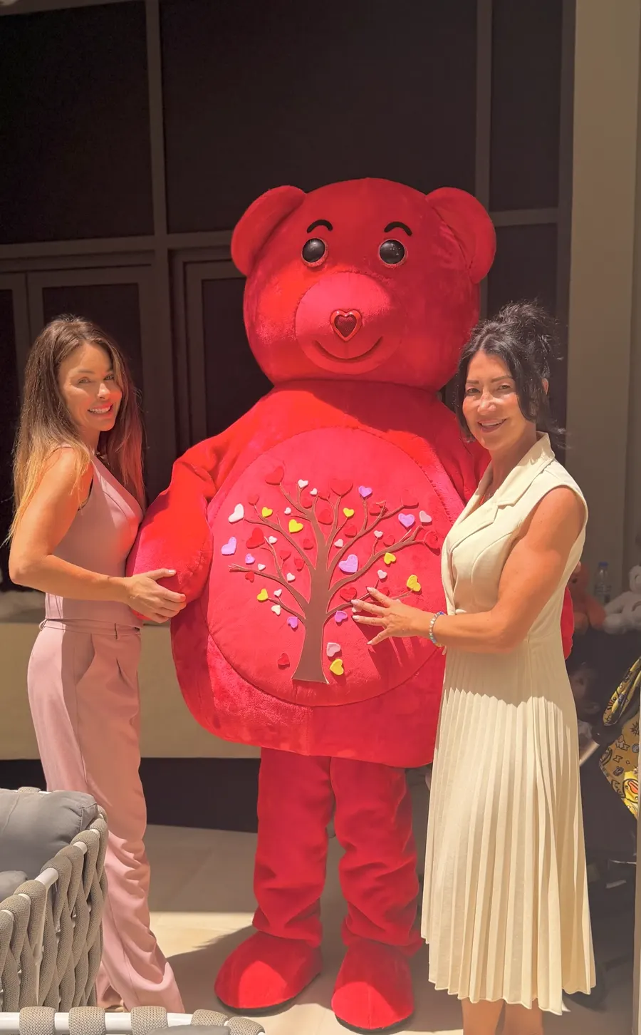 Two party guests posing with the red YogaBears mascot character